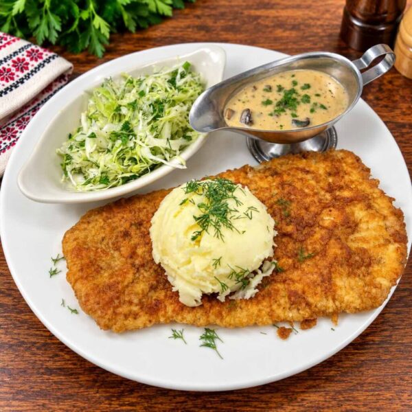 Golden Galician schnitzel with mashed potatoes, shredded cabbage salad and mushroom gravy.